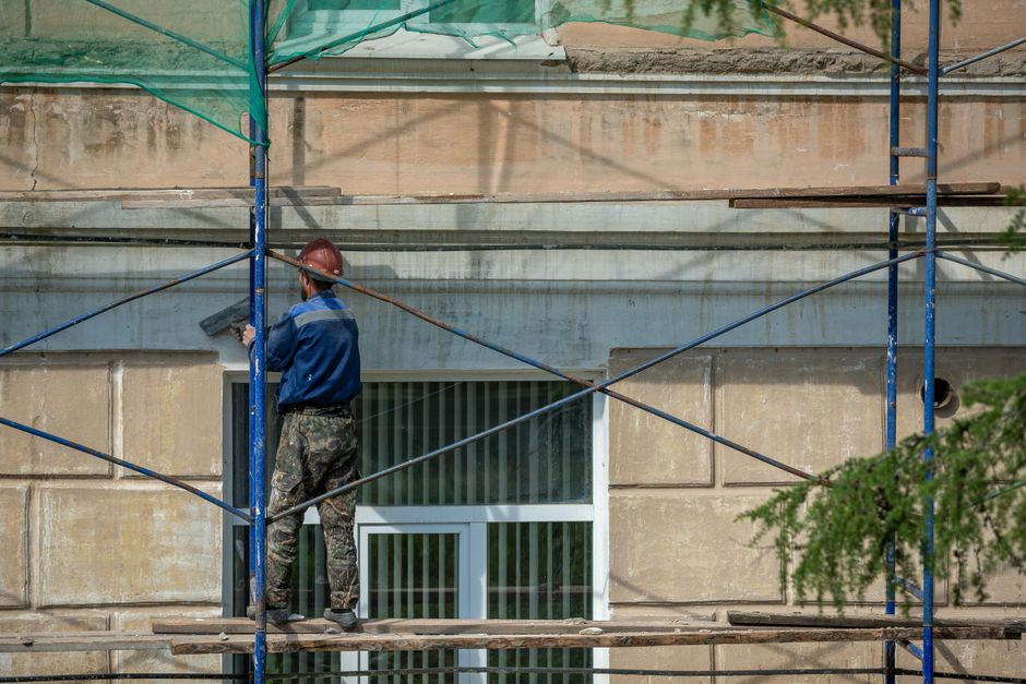 Pracovník na lešení pri montáži fasádneho zateplenia